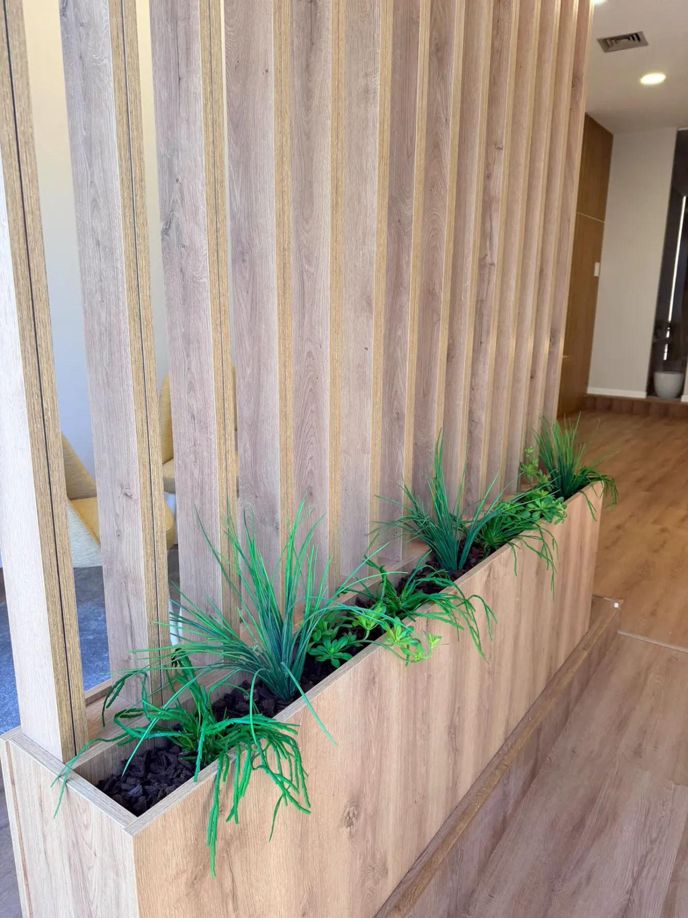 Claustra à tasseaux en bois avec jardinière, réalisée par Mestria